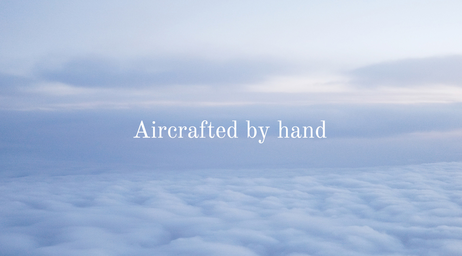 Private jet flying above clouds with “Aircrafted by hand” message, luxury aviation branding