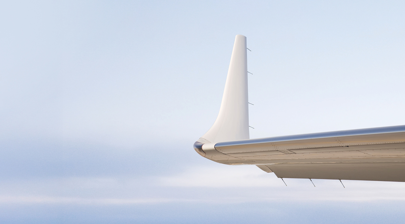 Private jet wingtip above clouds, showcasing sleek aircraft design and aerodynamic performance