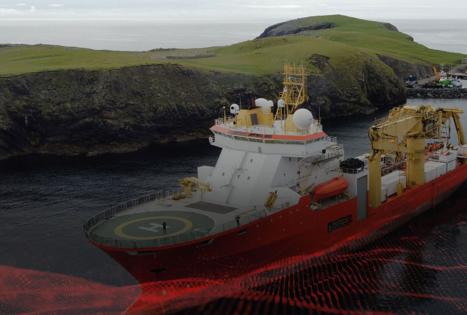 Offshore survey vessel operating near a rocky coastline during marine industrial operations