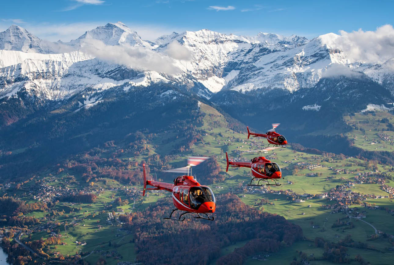 Fleet of red helicopters flying over mountain valley aviation operations